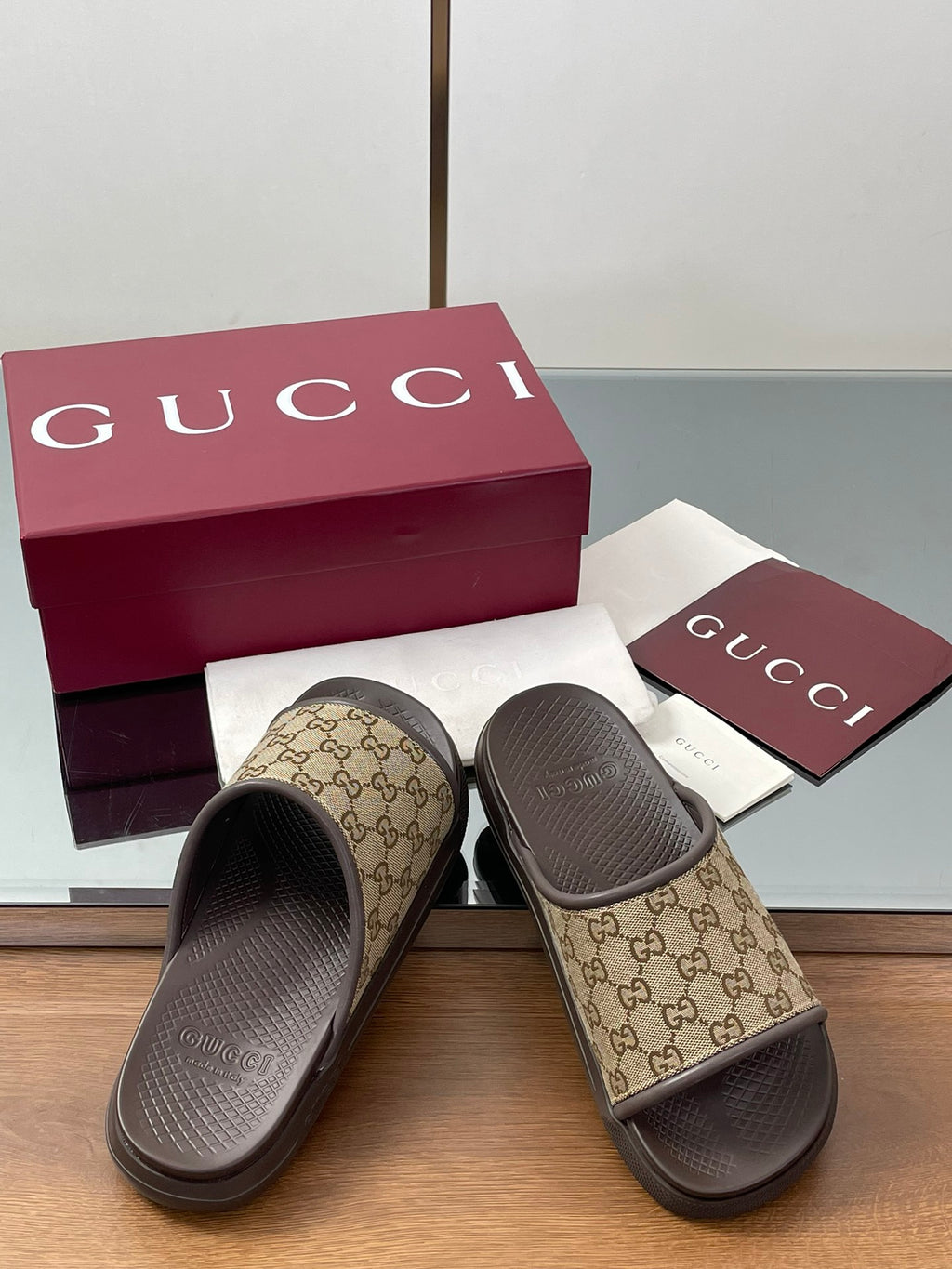 Gucci slide sandals with tan GG canvas uppers and dark rubber soles