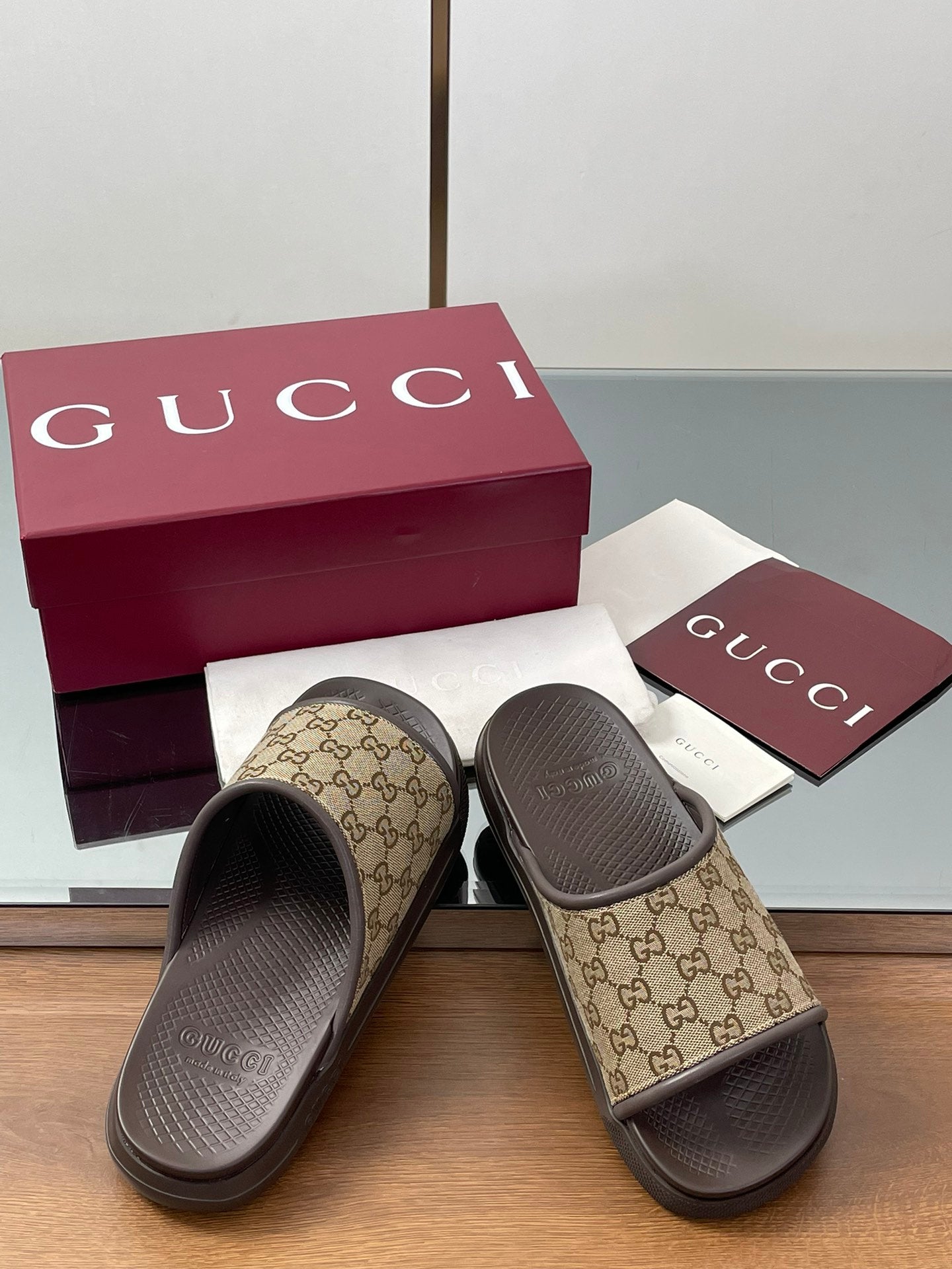 Gucci slide sandals with tan GG canvas uppers and dark rubber soles
