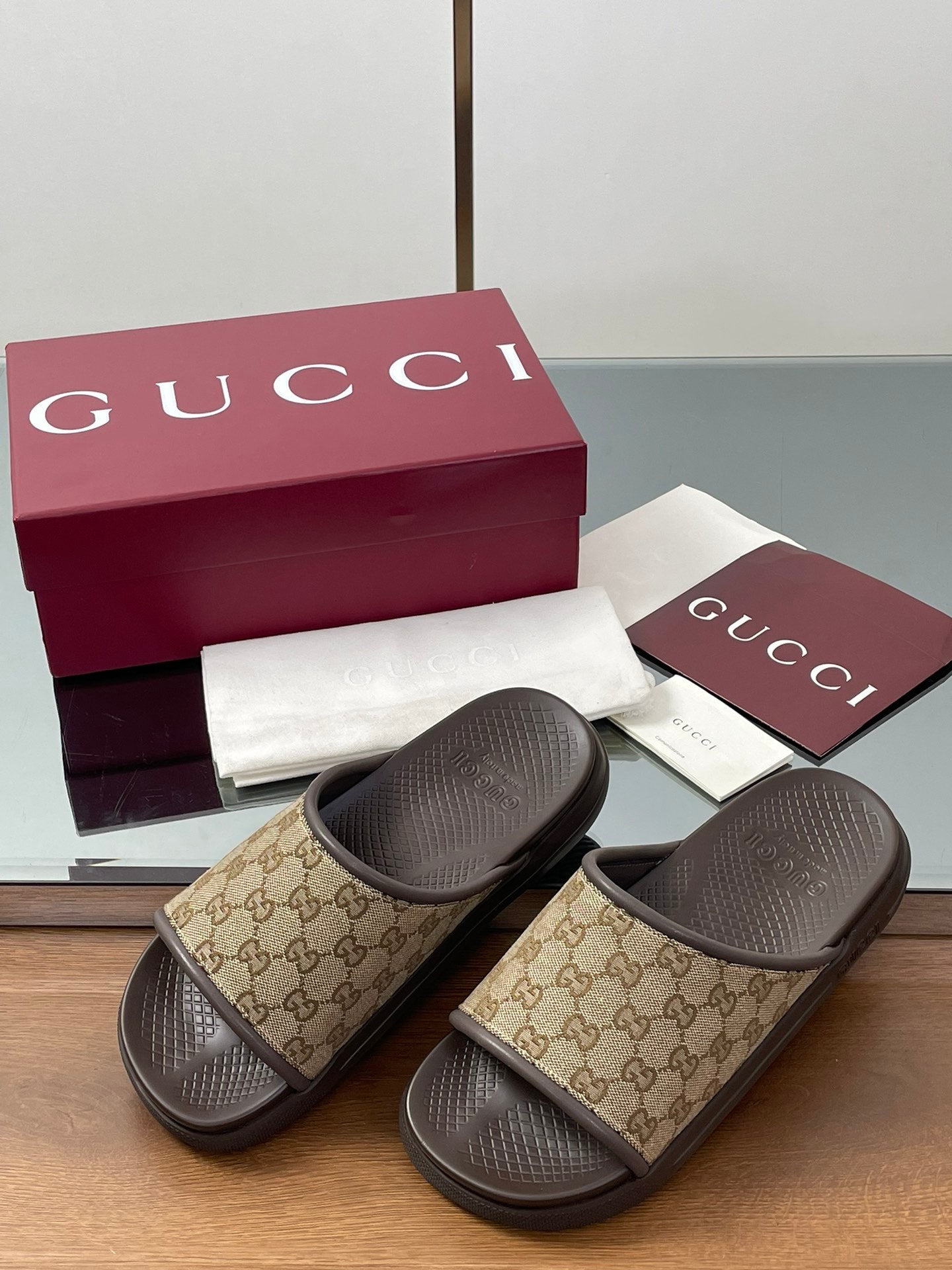 Gucci slide sandals with tan GG canvas straps and dark rubber outsoles