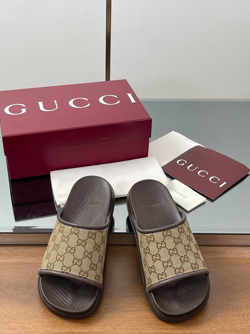Gucci slide sandals with tan GG monogram straps and dark molded rubber footbeds