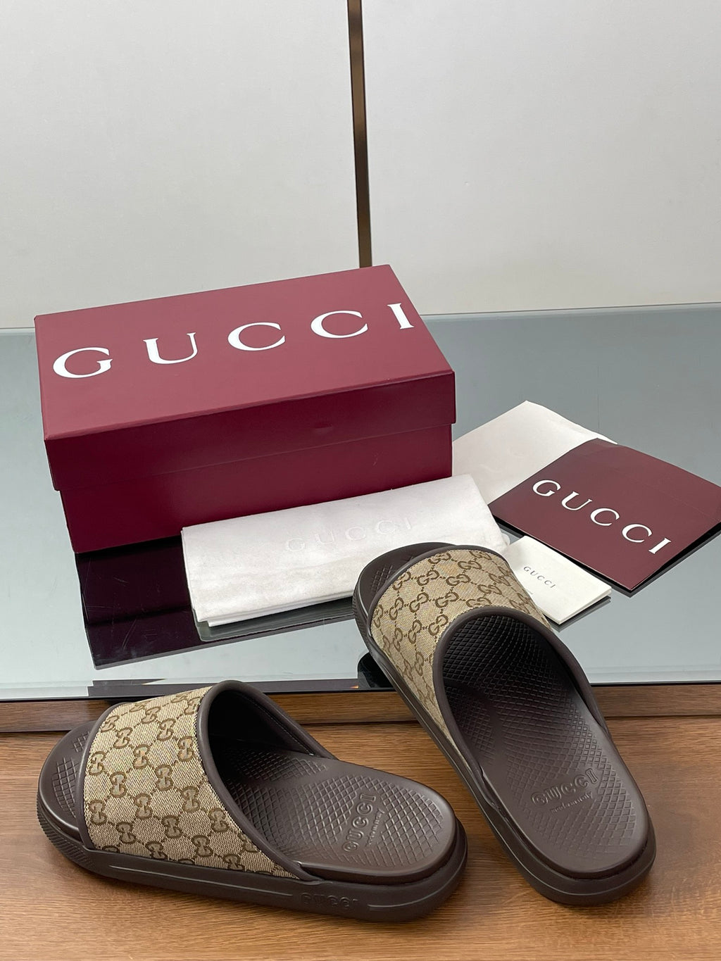 Gucci slide sandals with tan GG canvas straps and dark rubber slide soles