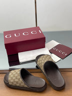 Gucci slide sandals with tan GG canvas straps and dark rubber slide soles