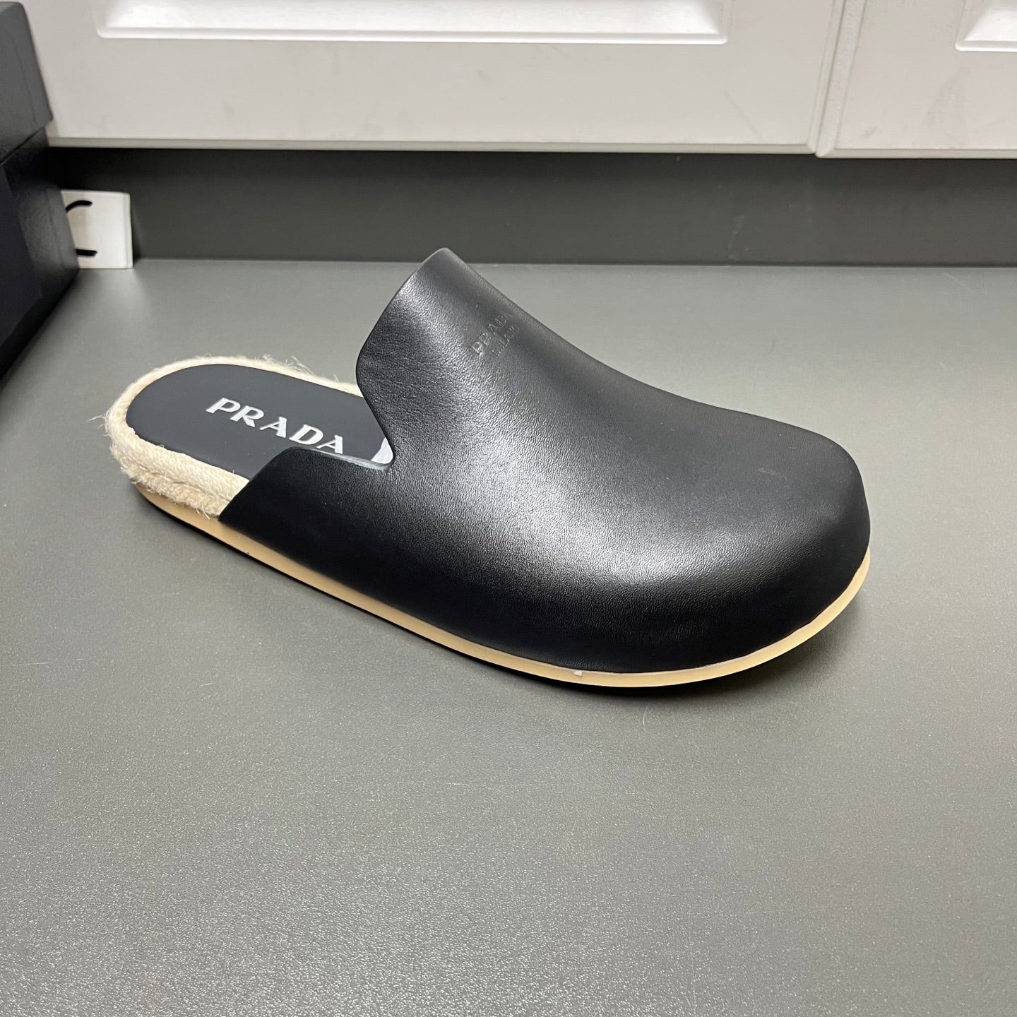 Prada black slip-on slide sandal with curved upper, beige shearling and tan trim