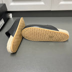 Prada black slide sandals, visible textured outsole and tan sole edge