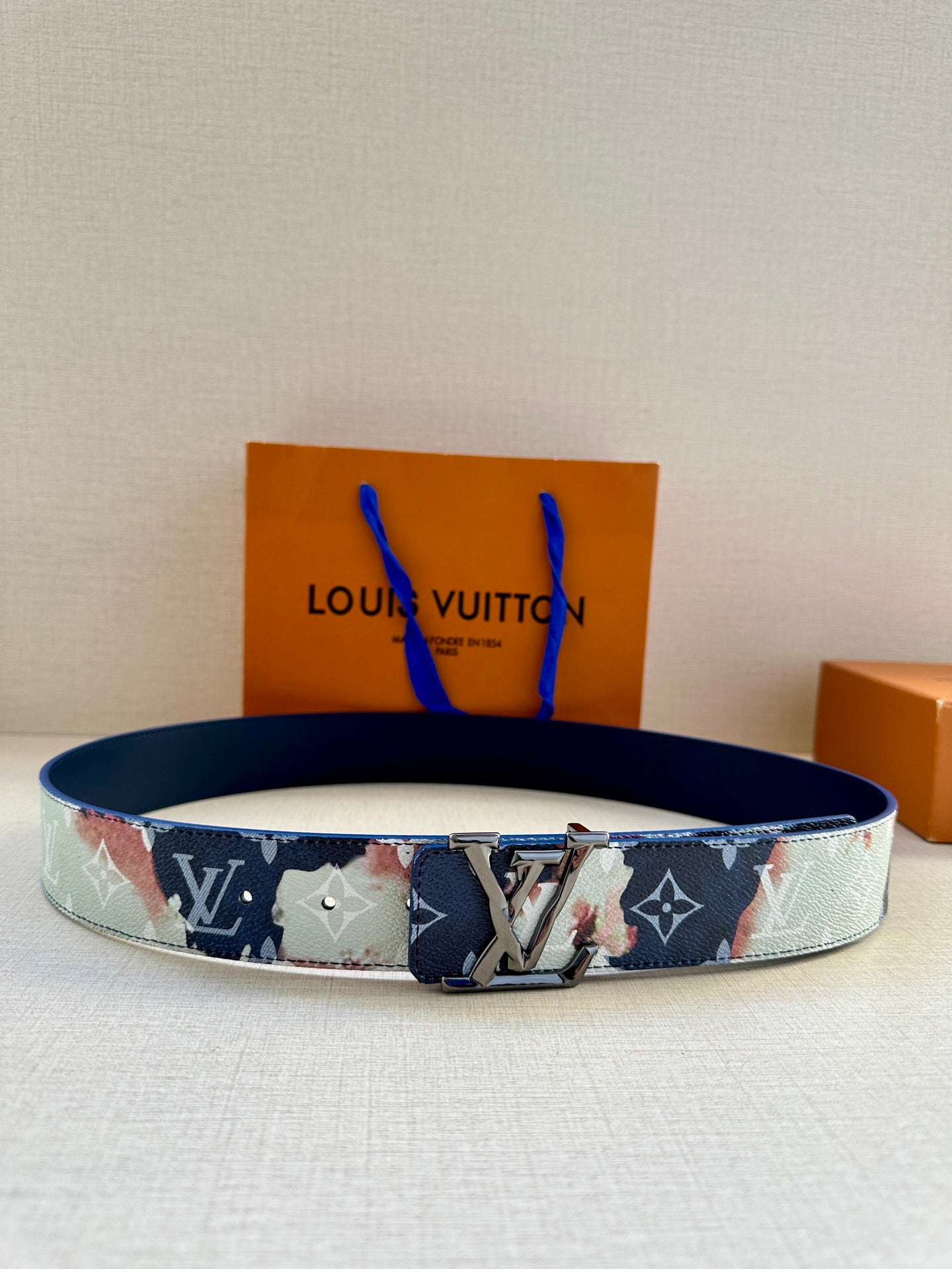 Louis Vuitton belt with blue-and-light monogram print and silver buckle, shown on surface