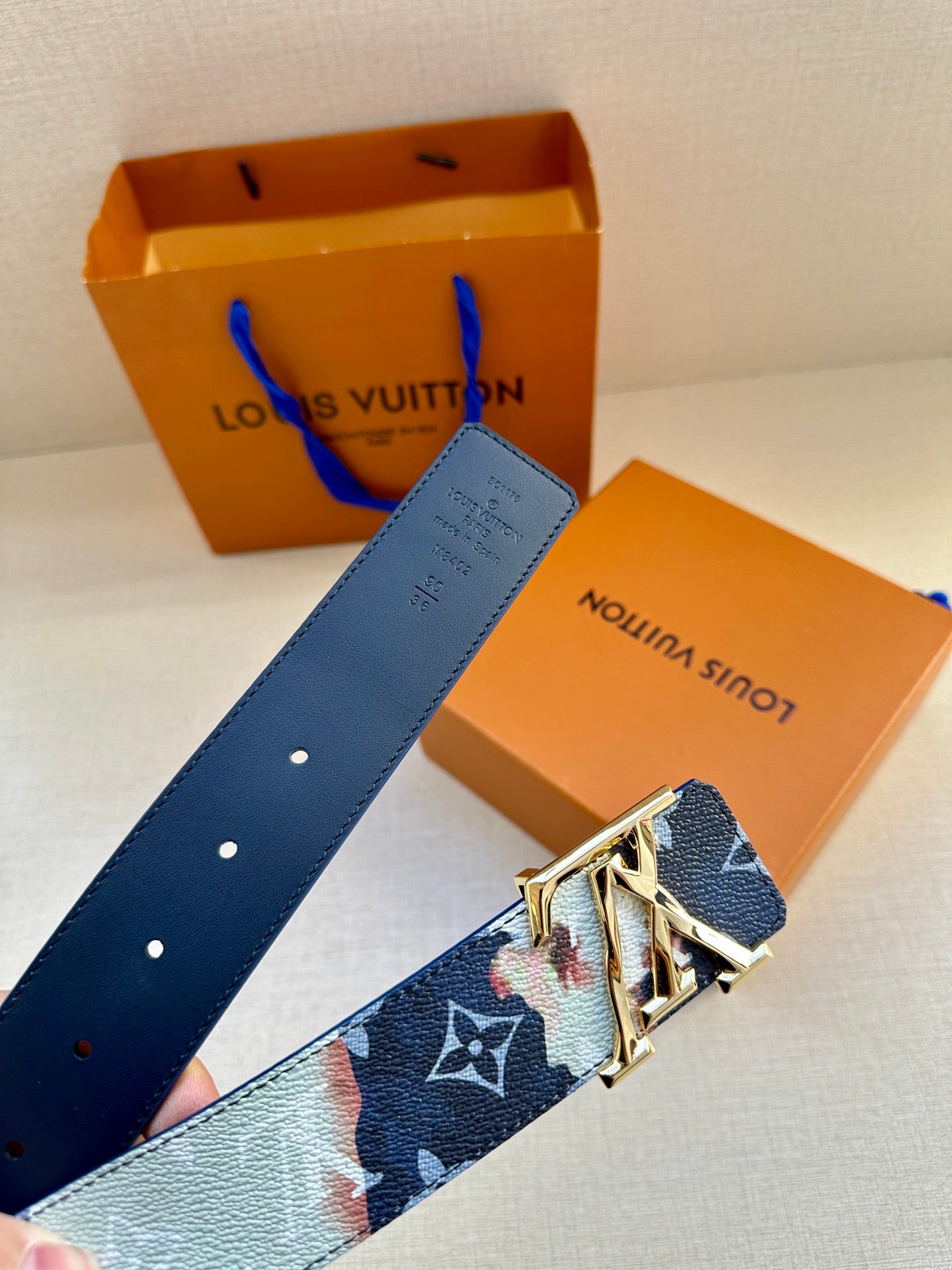 Louis Vuitton belt end with blue leather strap holes and gold-toned buckle, with tag