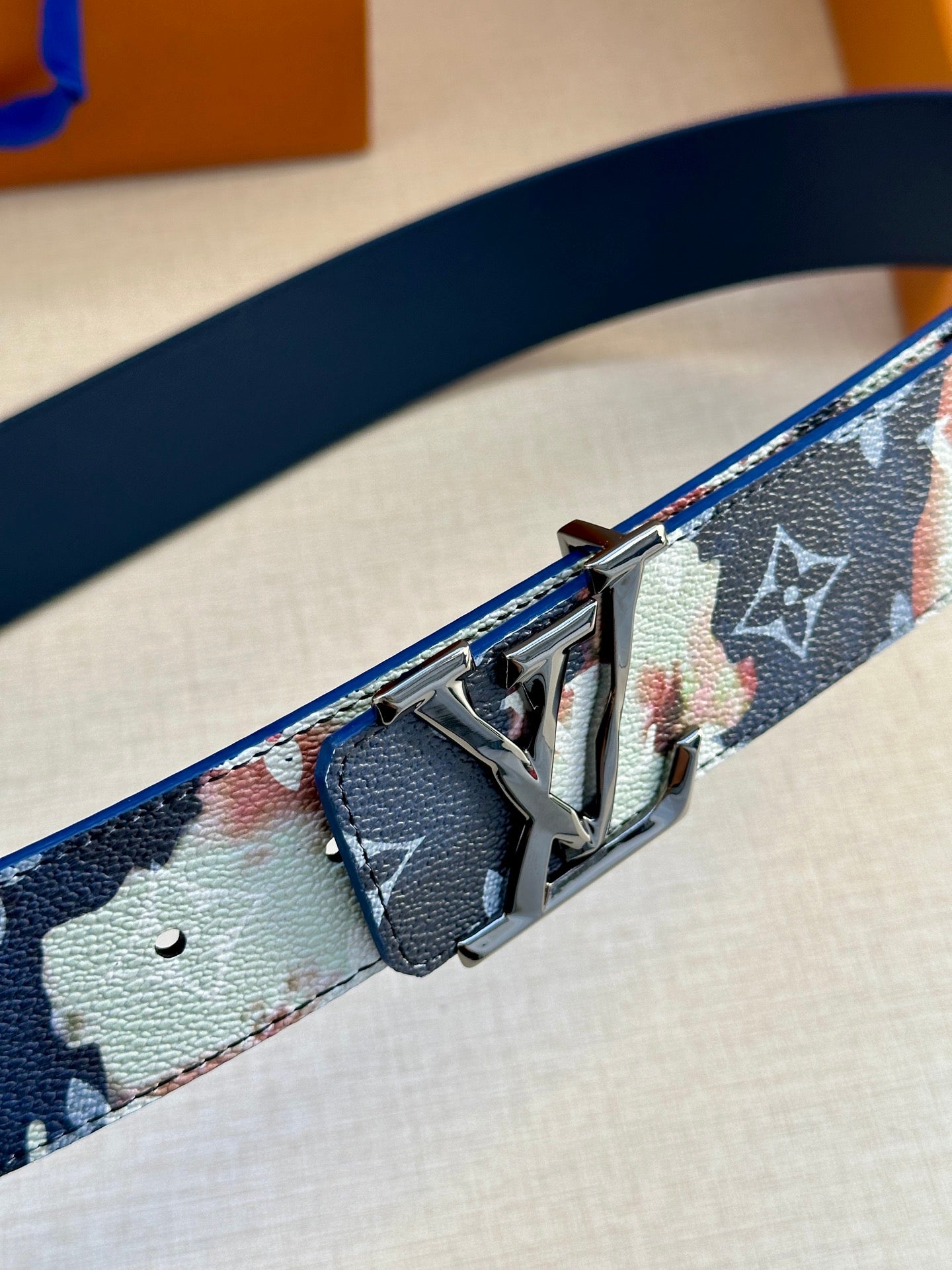 Louis Vuitton belt close-up: blue-and-light monogram strap with silver buckle and prongs