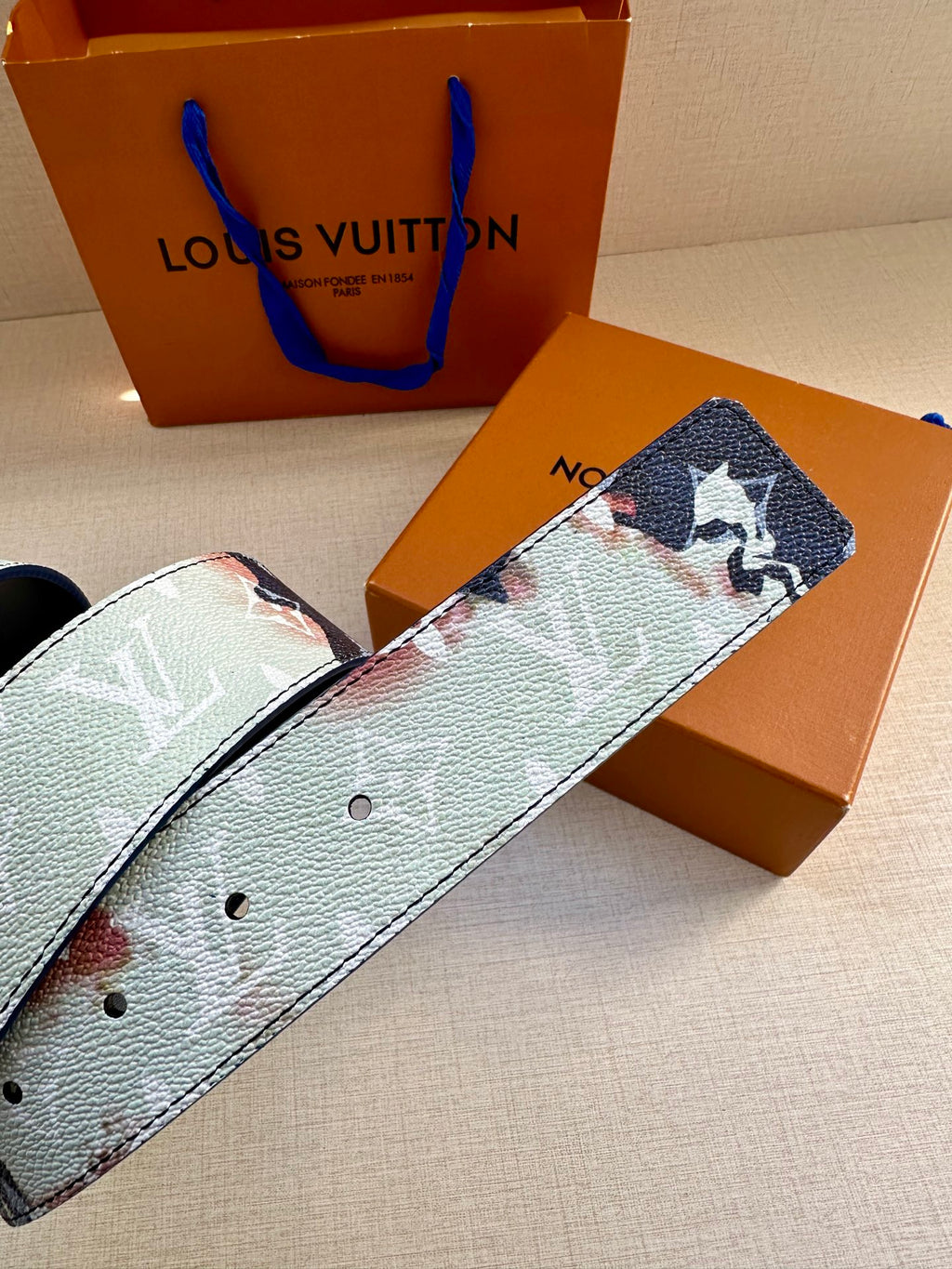 Louis Vuitton belt close-up: blue-and-light monogram strap with stud holes