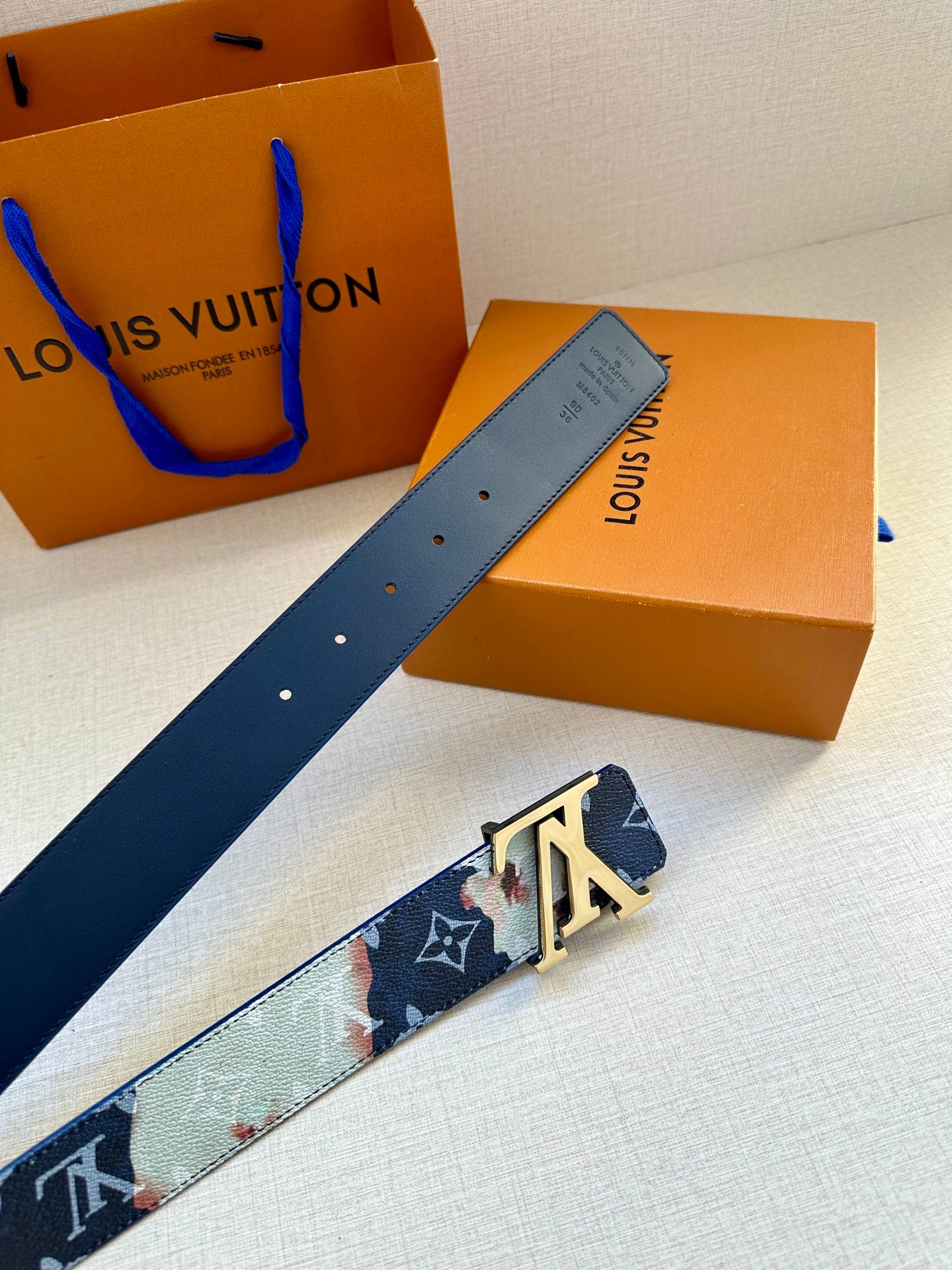 Louis Vuitton belt strap detail in navy, light blue, and floral prints with silver buckle