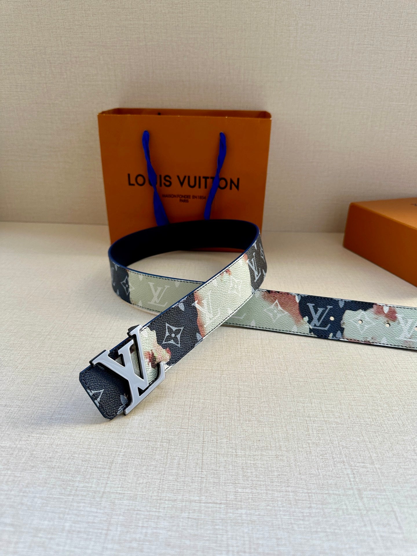Louis Vuitton belt with navy and light blue patchwork pattern and LV buckle; laid flat