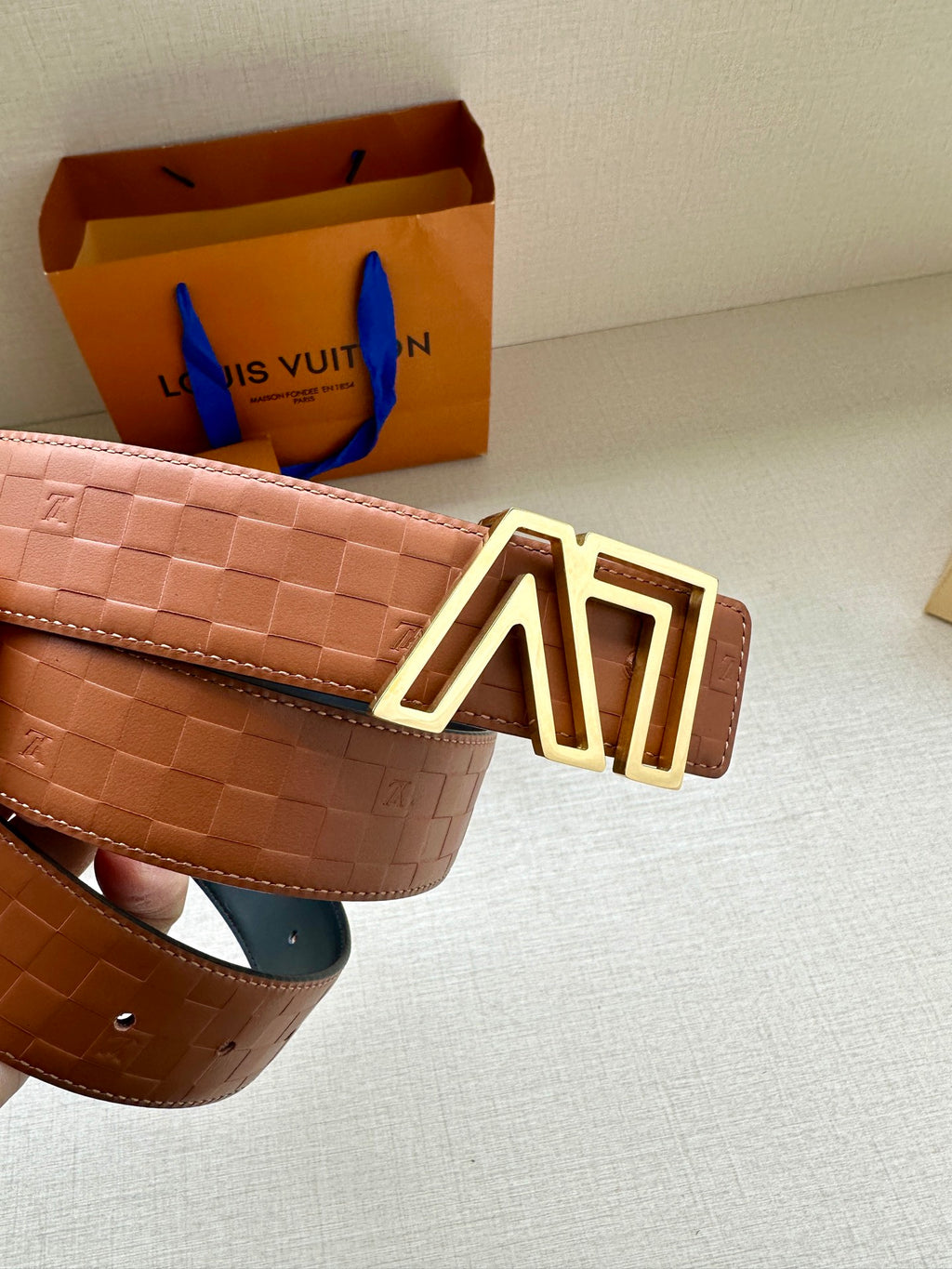 Tan patterned leather belt with gold-tone LV buckle and adjustable keeper