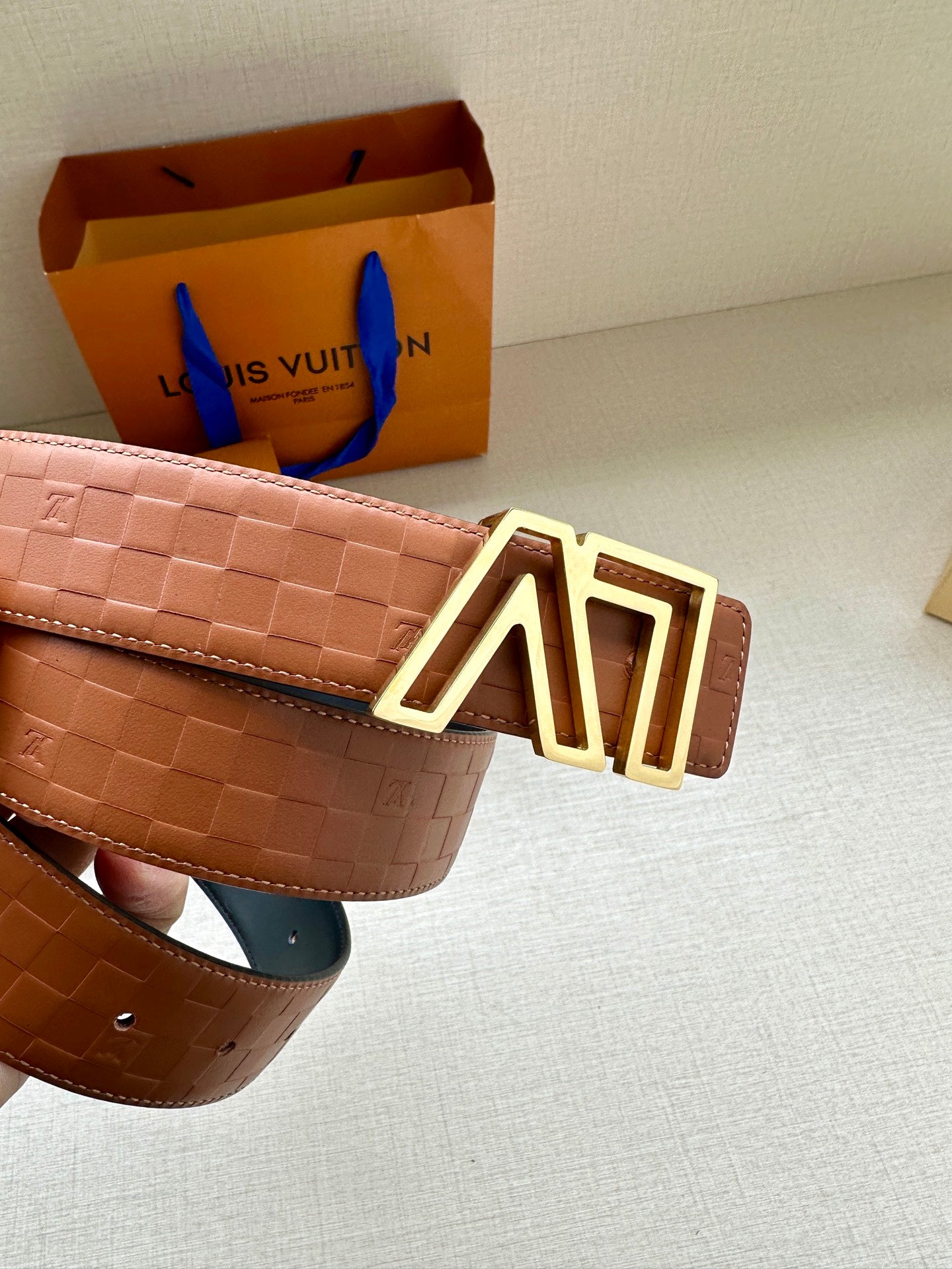 Tan patterned leather belt with gold-tone LV buckle and adjustable keeper