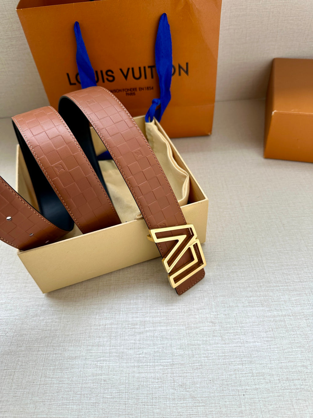 Tan patterned leather belt with gold-tone LV buckle and layered straps