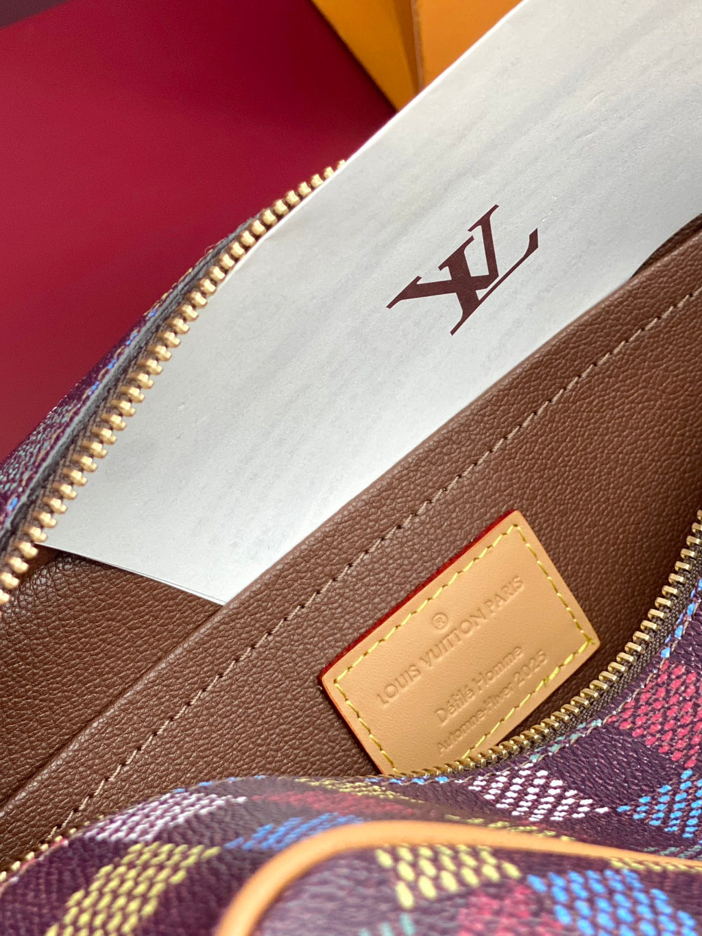 Louis Vuitton leather label on brown panel near check-pattern bag edge