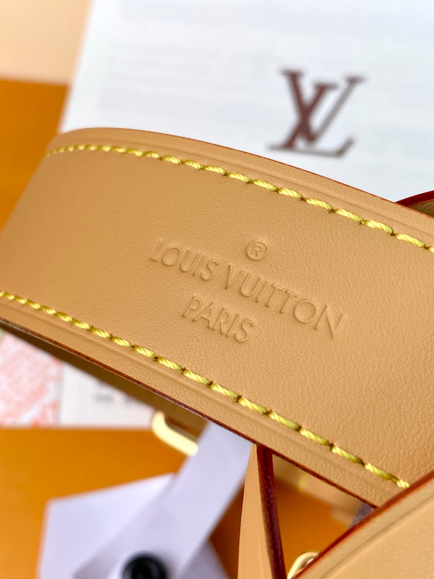 Tan leather strap end with embossed 'LOUIS VUITTON PARIS' text