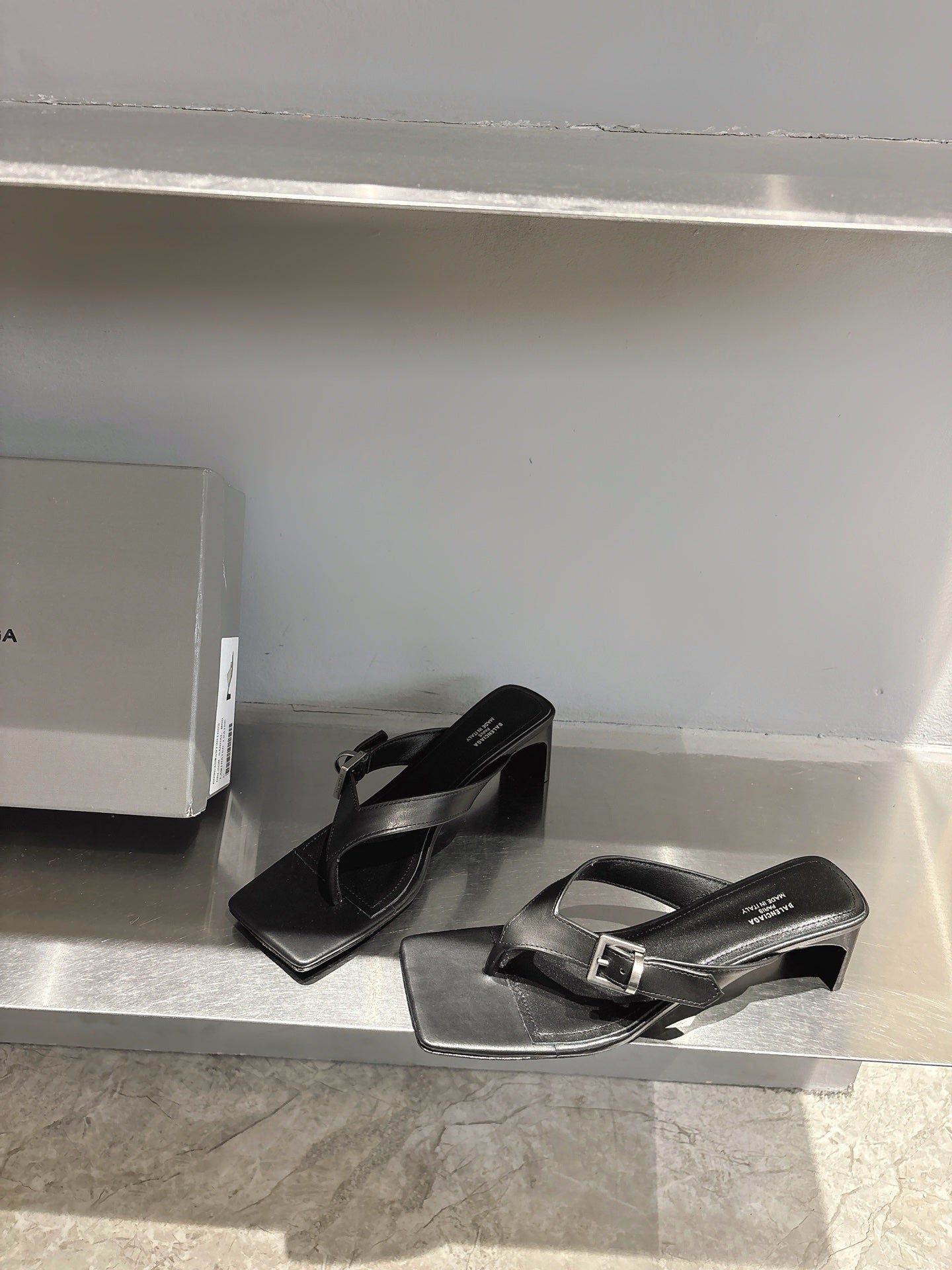 Balenciaga black leather sandals with silver buckle and square toe, one pair on shelf