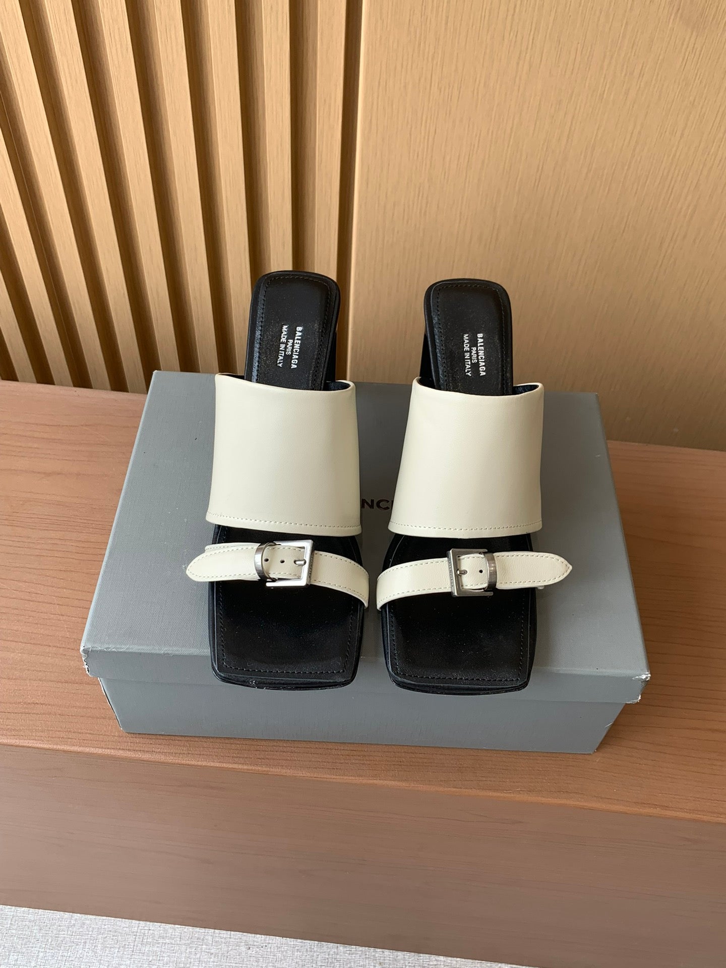 Balenciaga two-strap sandals with cream straps, black footbed, and buckle closure