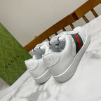 White Gucci sneakers with green and red web stripe and embossed logo on tongue.