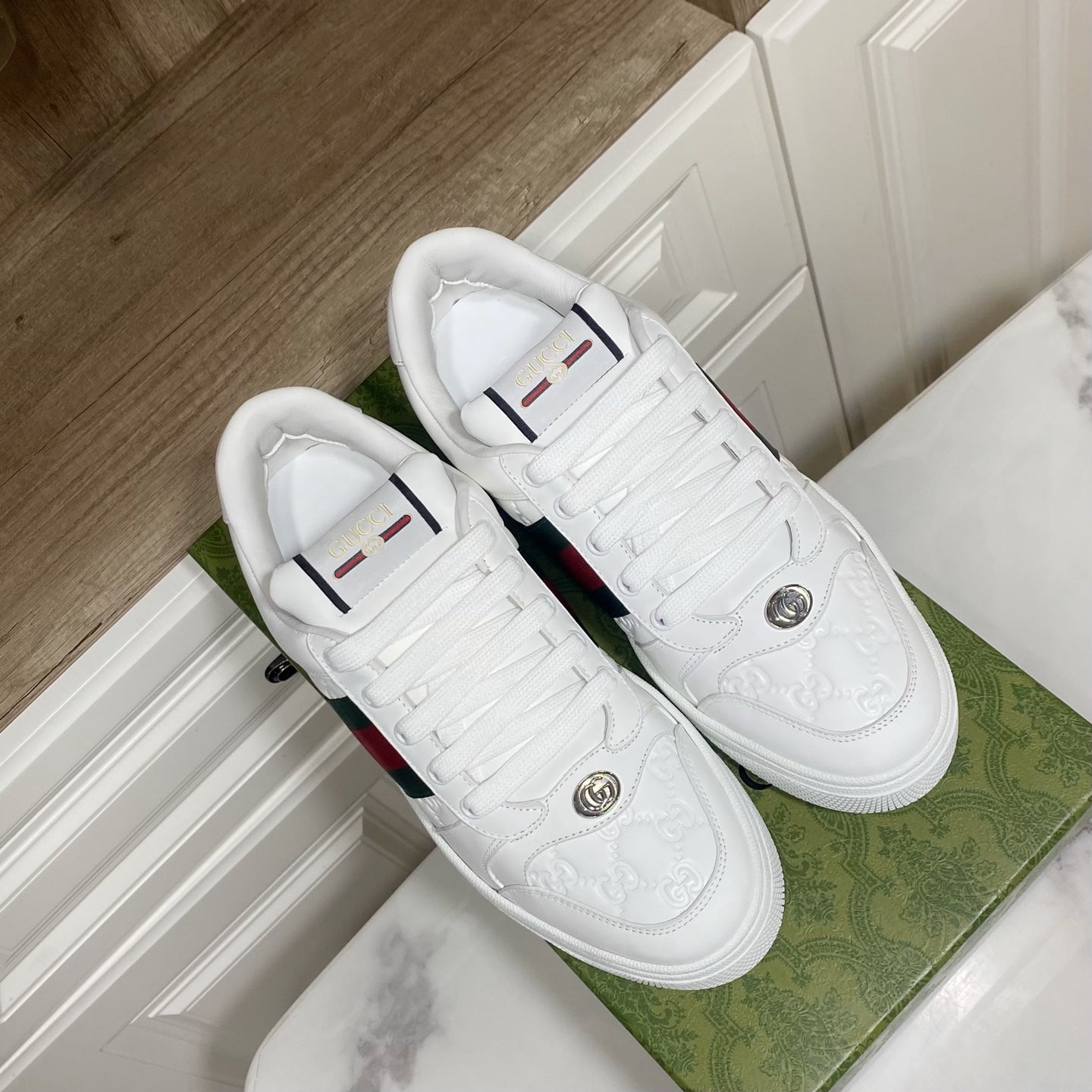 Pair of white Gucci sneakers with green-red web stripes, lace-up and round toe.