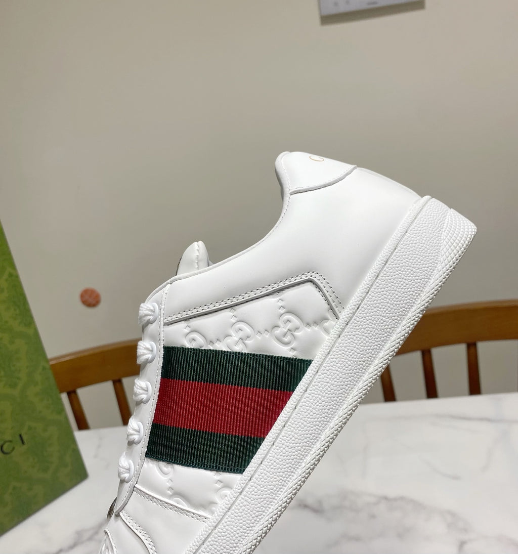 White Gucci low-top sneaker with green-red web stripe and textured leather upper.