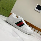 White Gucci low-top sneakers with green-red-green web stripe panel on the side.