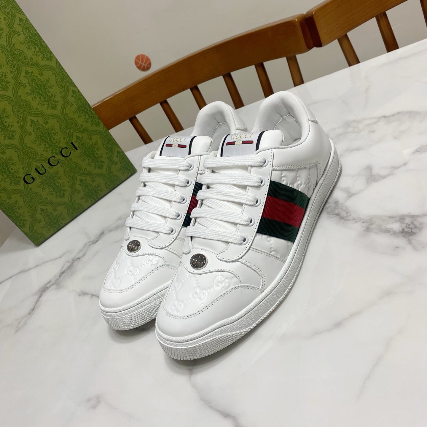 White Gucci lace-up sneakers with green-red web stripe and stitched logo details.