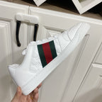 White Gucci sneaker with green-red web stripe, visible midsole and lace-up front.