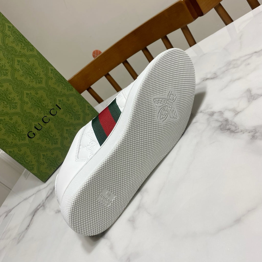 White Gucci sneakers outsole with textured grip; side has green and red web stripe.