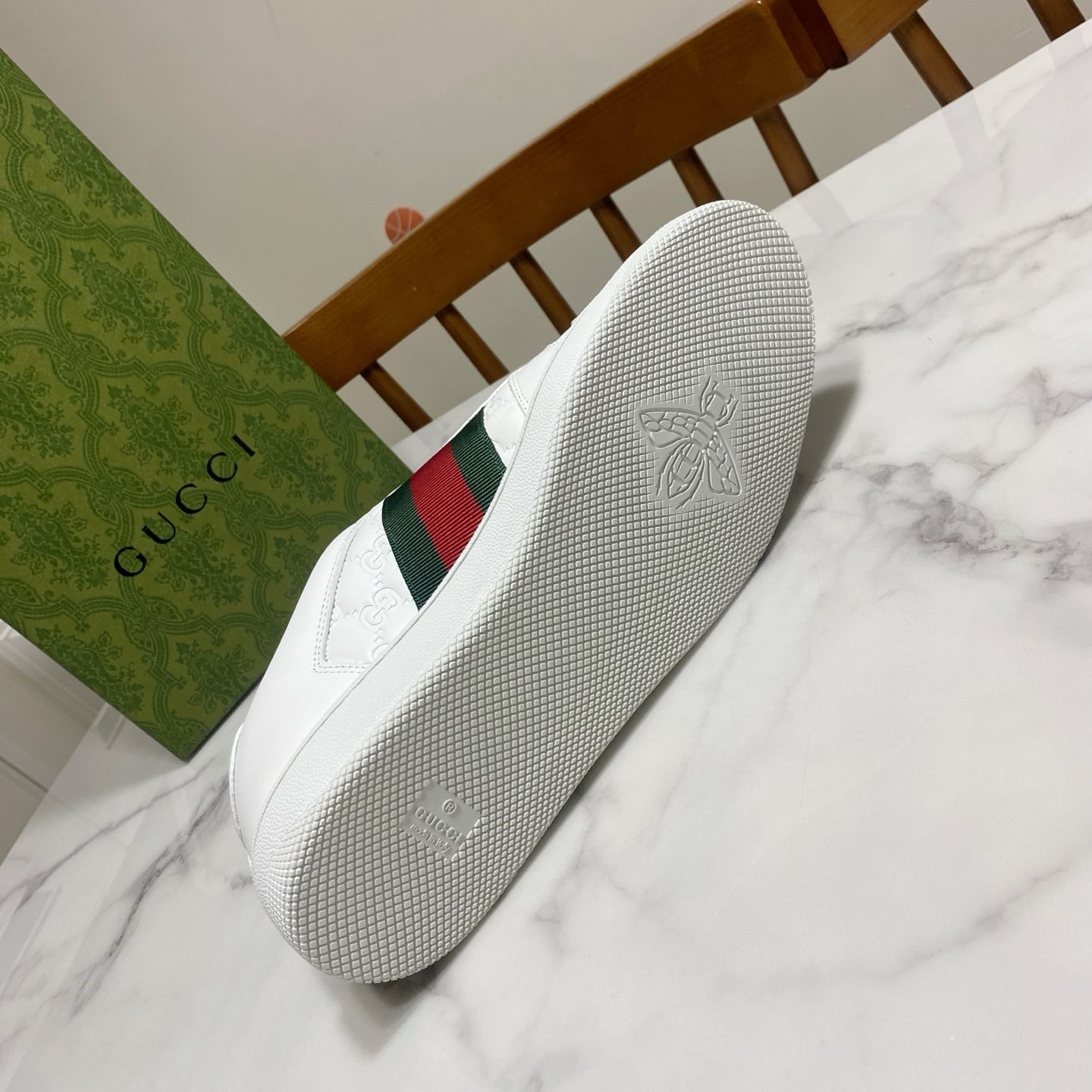 White Gucci sneakers outsole with textured grip; side has green and red web stripe.