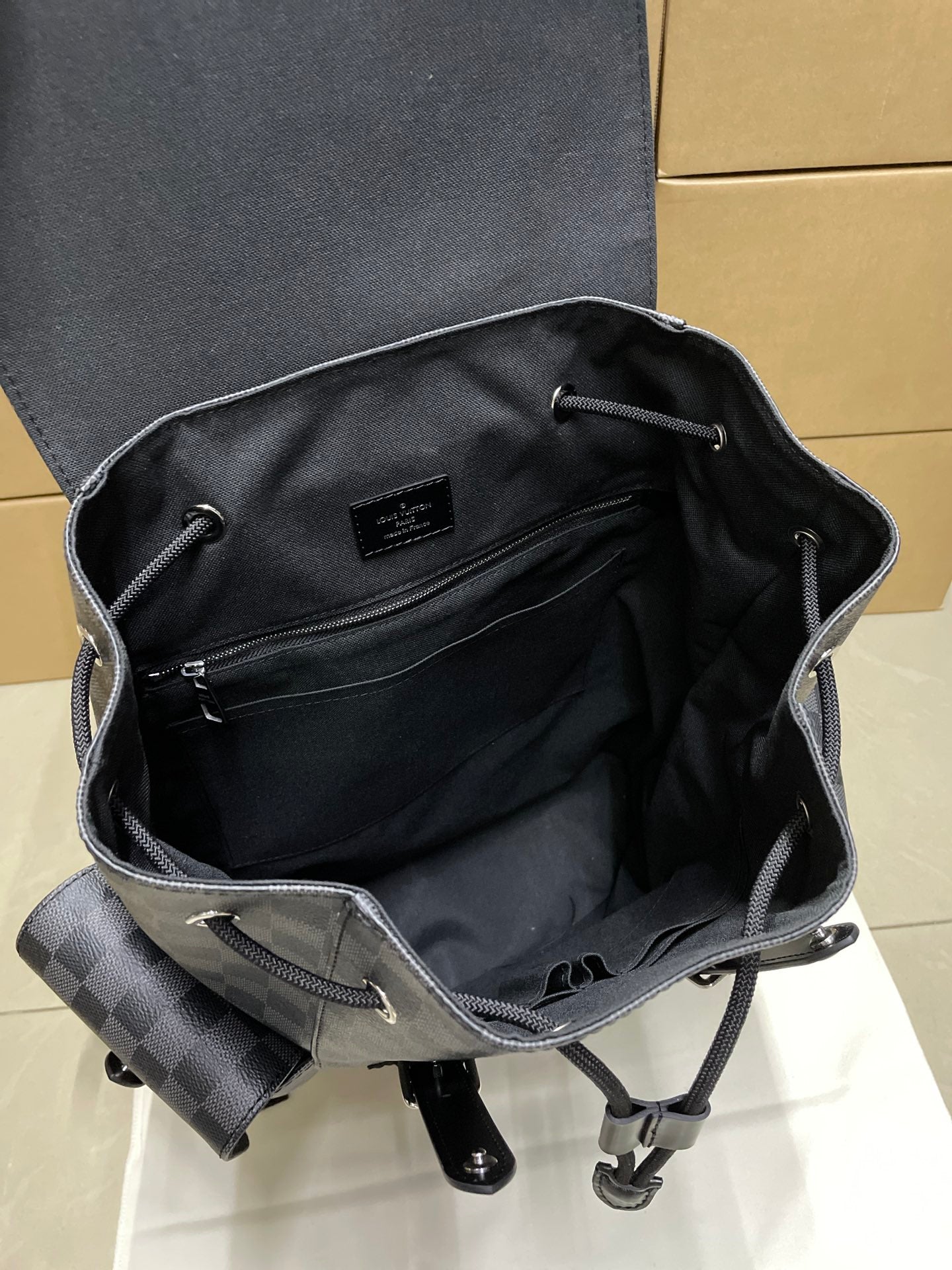 Louis Vuitton checkered canvas backpack interior with zipper pocket and leather trim, dark