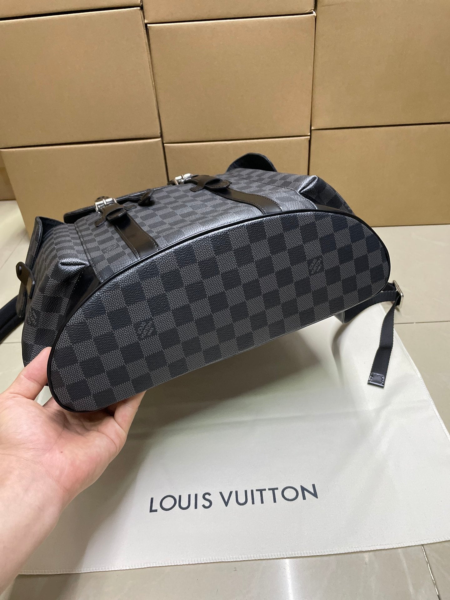 Louis Vuitton Damier-check backpack with top handle, rounded body, and zipper closure