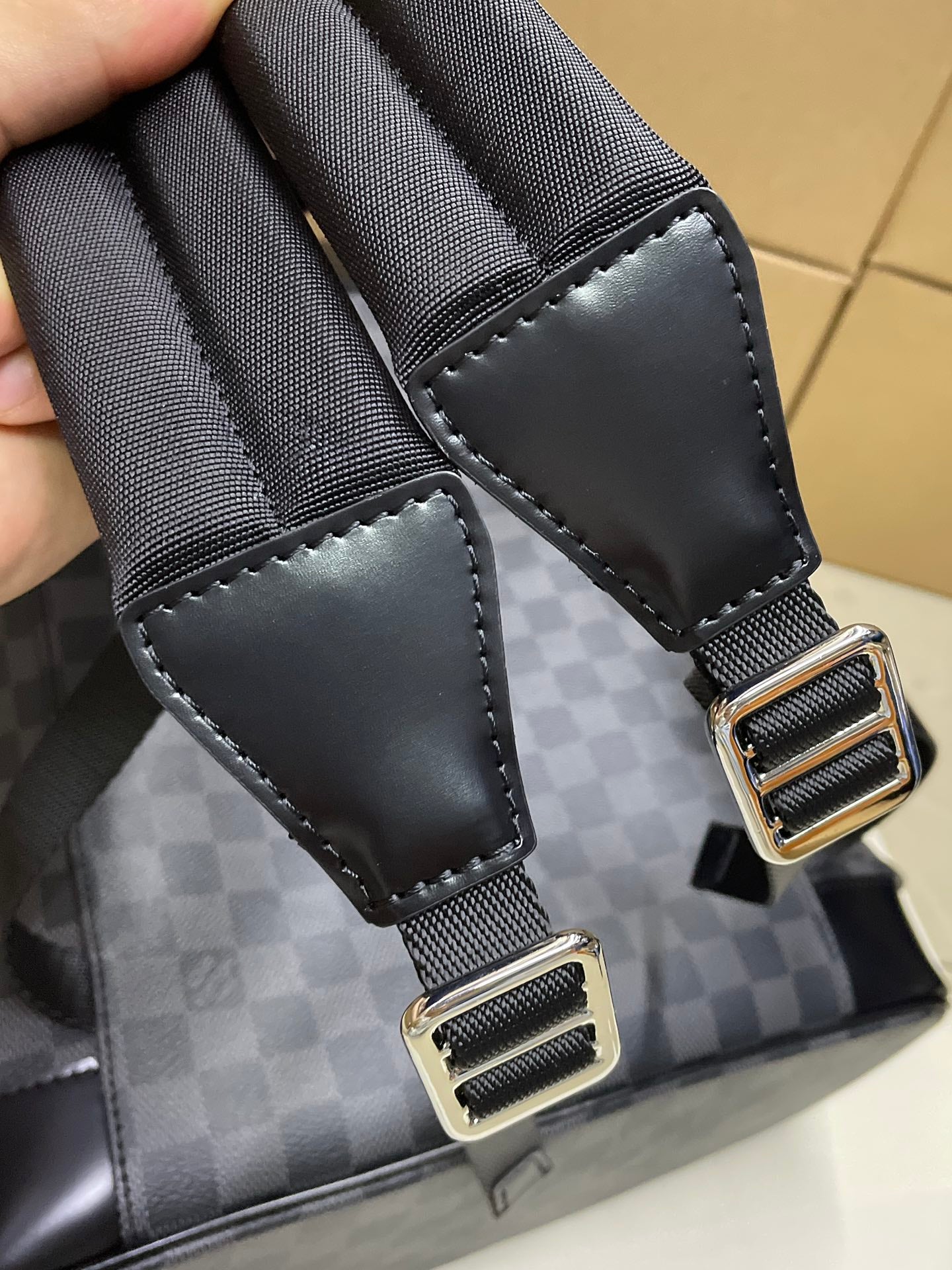 Louis Vuitton Damier-check backpack close-up of webbing straps with metal buckles