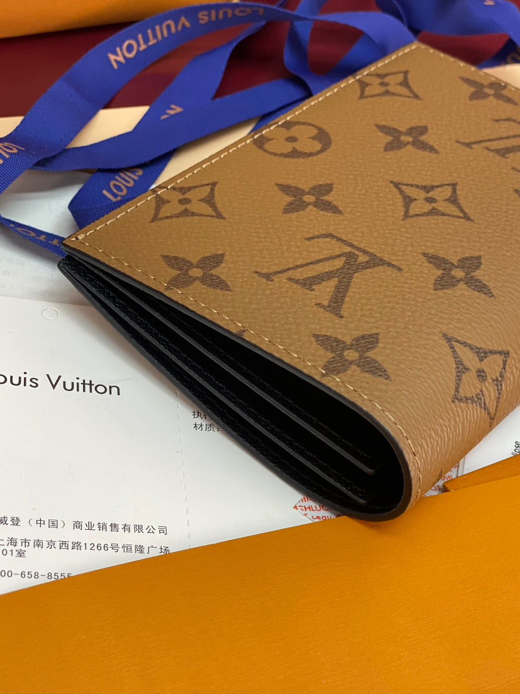 Small bag with tan monogram exterior, opened showing dark interior.