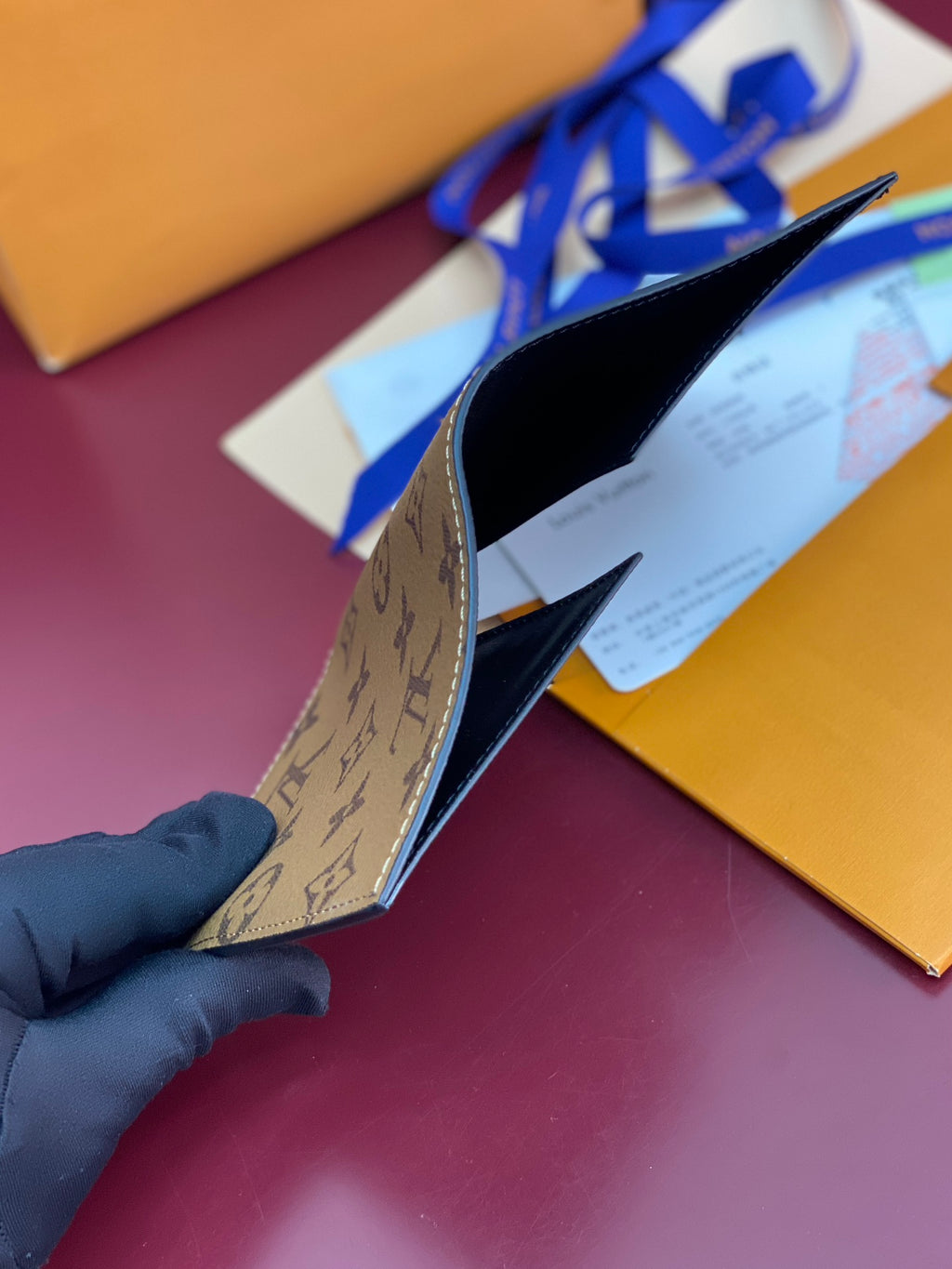 Small bag side view with patterned lining, held above gift boxes.