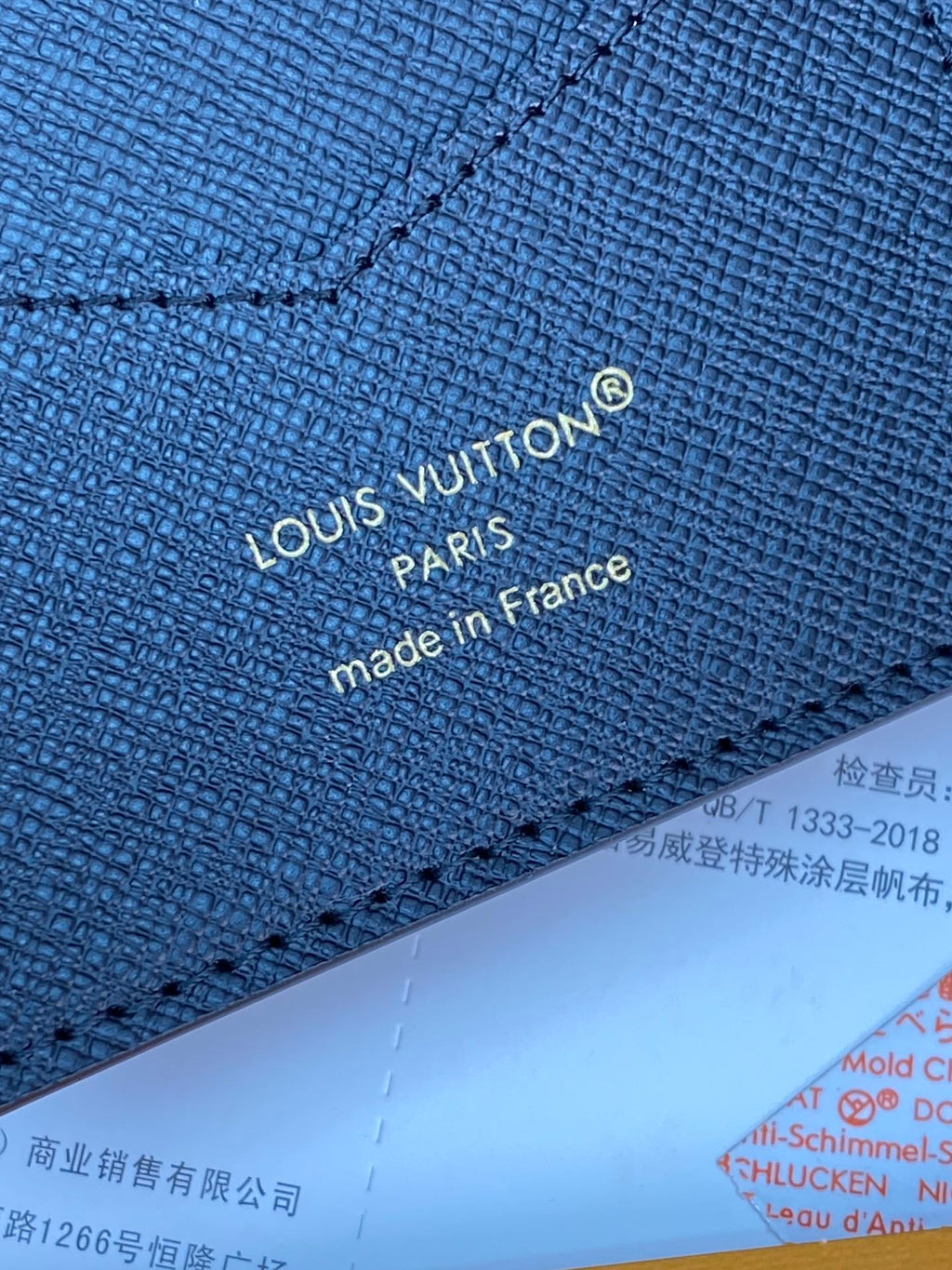 Small bag close-up of navy fabric with "Louis Vuitton" and "made in France".