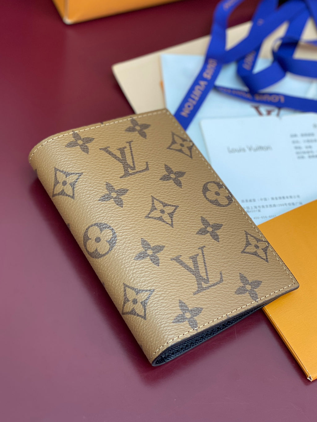 Small bag with beige monogram print, folded and tied near gift packaging.