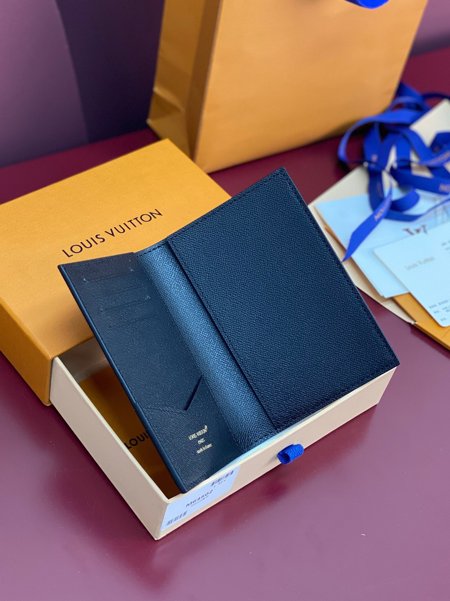 Small bag with textured navy exterior, shown in open gift box with ribbon.