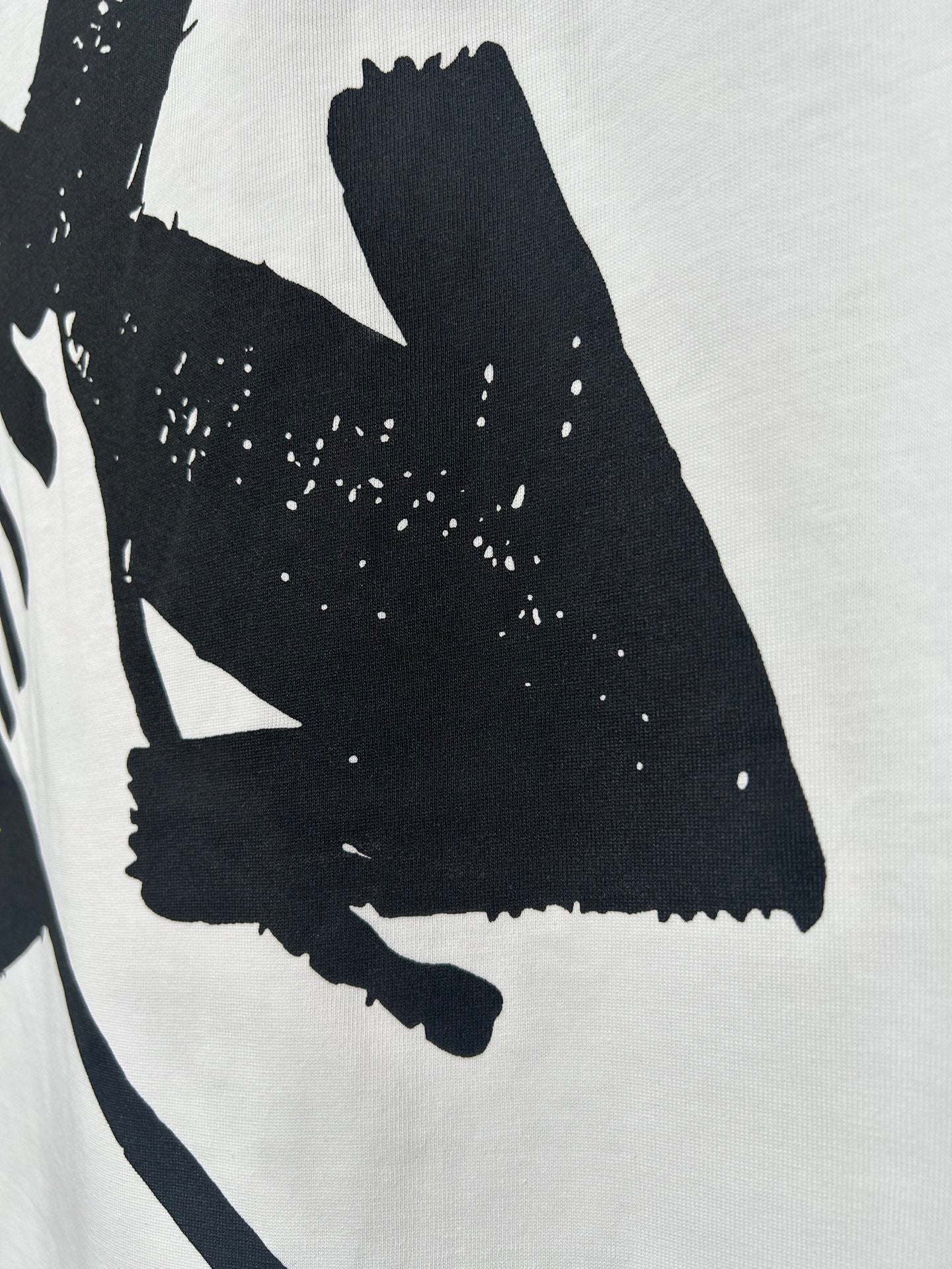 Off-white T-shirt close-up of large black graphic and speckled texture