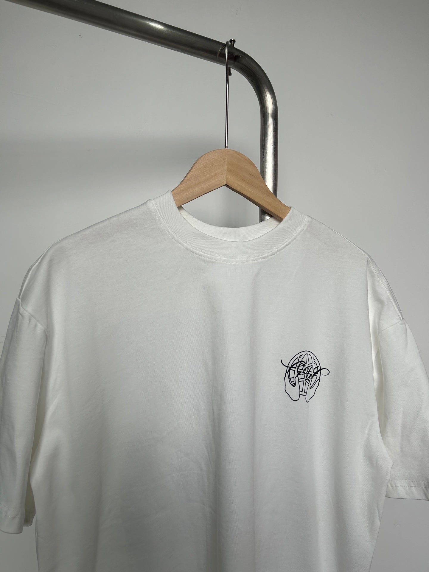 Off-white T-shirt close-up of neckline and small black logo at left chest
