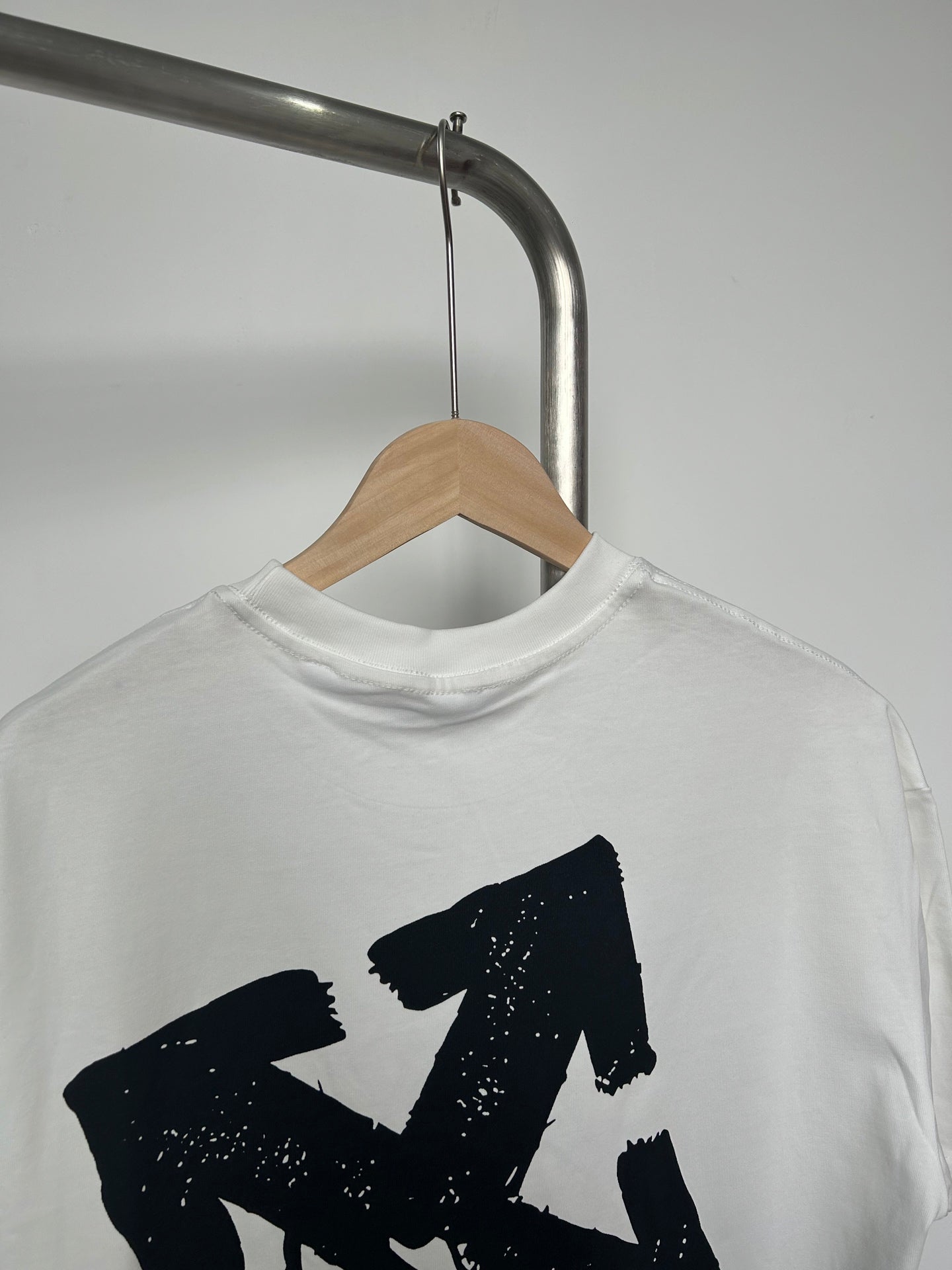 Off-white T-shirt showing large black graphic and crew neck