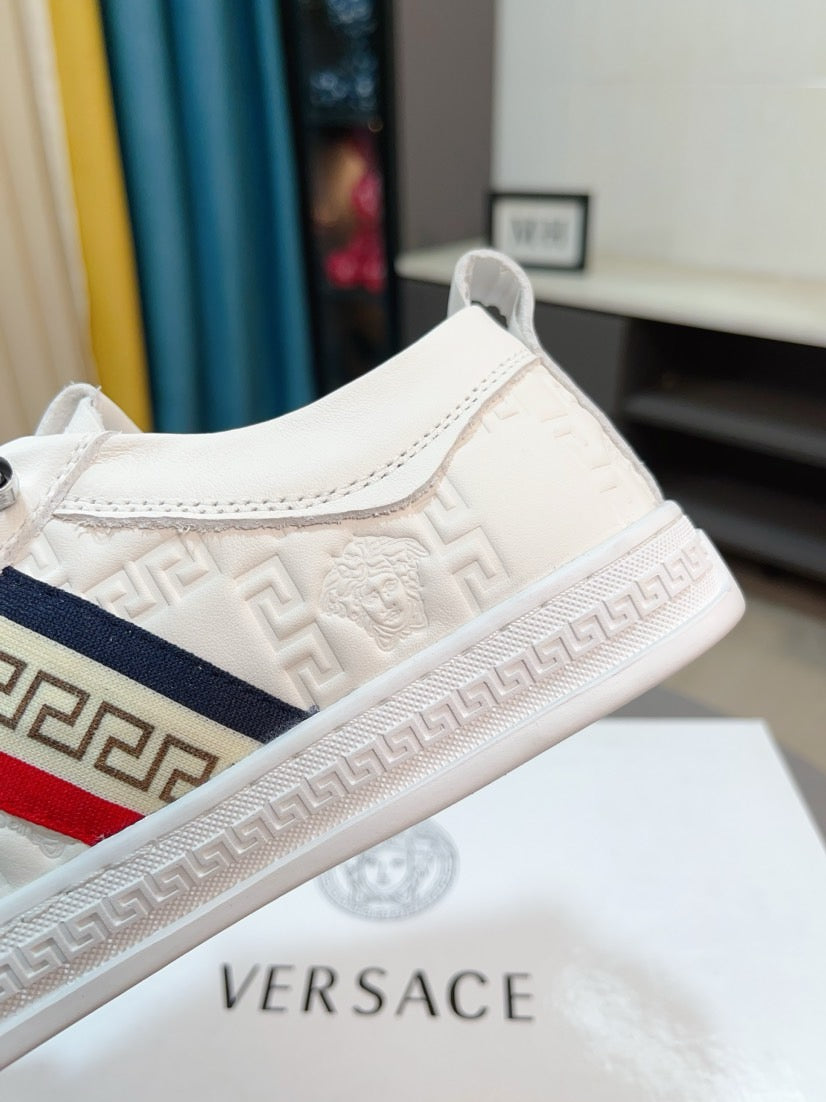 Side view of white luxury sneaker with Greek key detailing, red-and-navy side stripe.