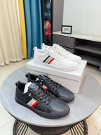 Pair of luxury sneakers, white and dark, low-top with red-and-blue side stripe.