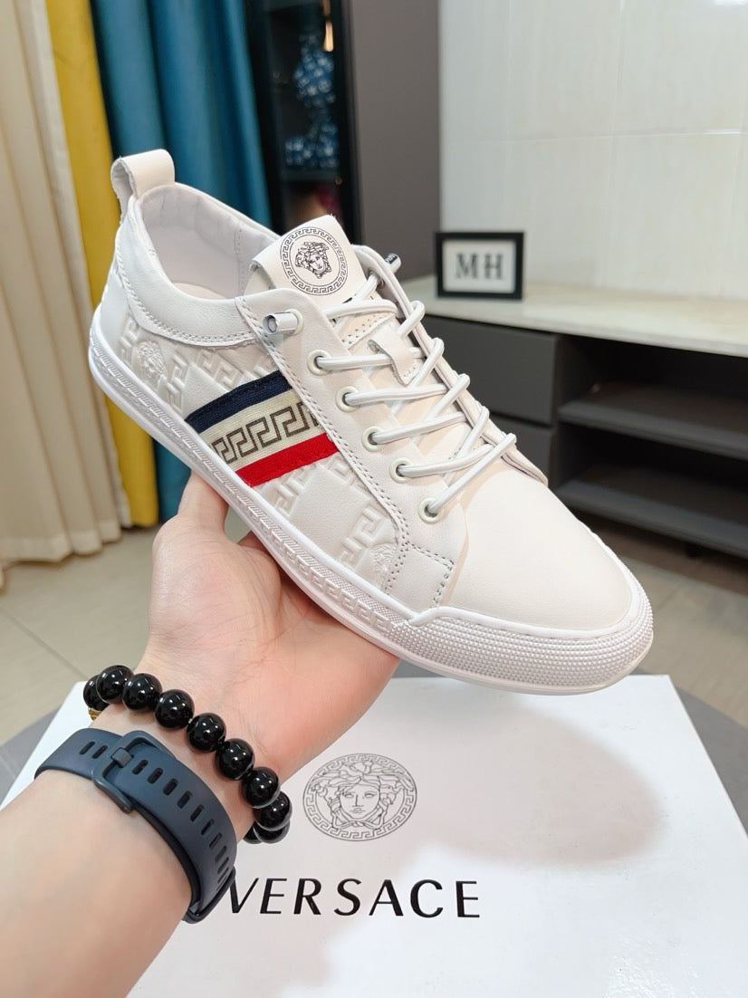 White luxury sneaker on hand, lace-up with embossed texture and Greek key side panel.