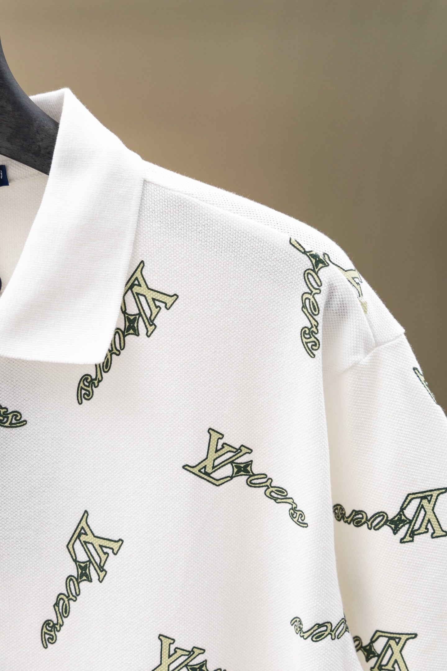 White polo shirt sleeve with repeating Louis Vuitton-style logo print
