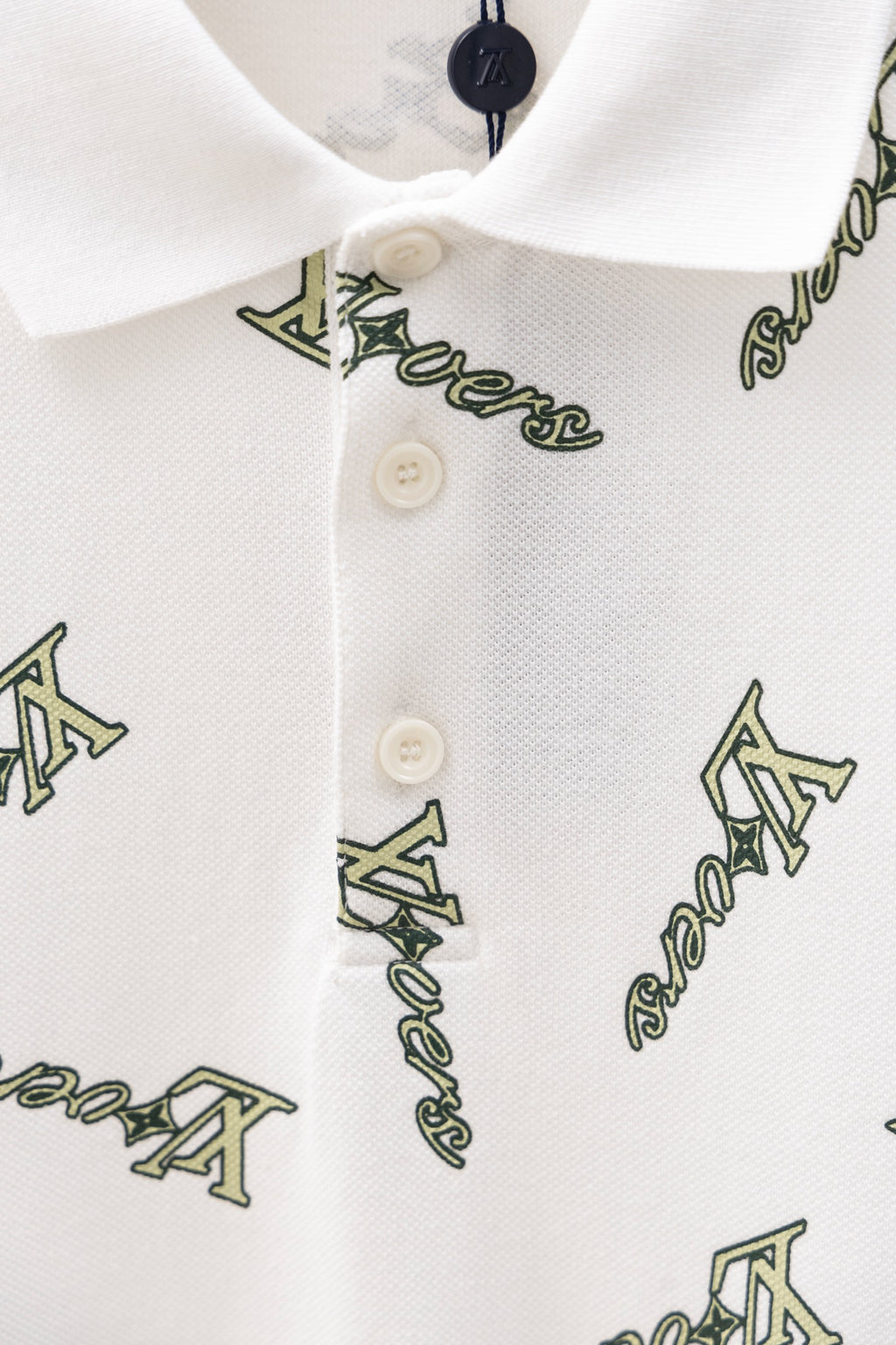 White polo shirt button placket and collar with Louis Vuitton-style logo print
