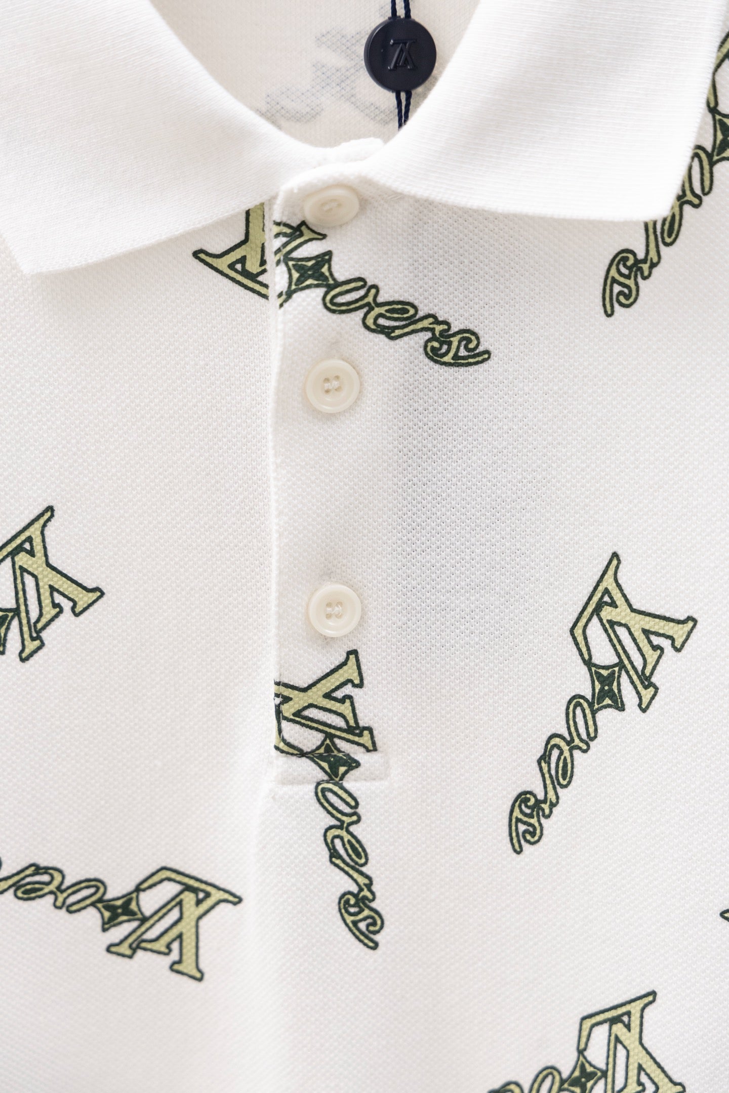 White polo shirt button placket and collar with Louis Vuitton-style logo print