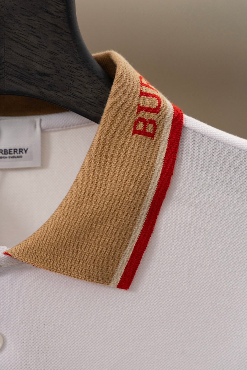 Burberry polo shirt sleeve detail: tan cuff with red “B” stripe