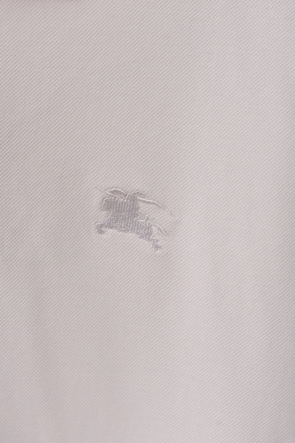 Burberry polo shirt fabric close-up with small embossed horse logo