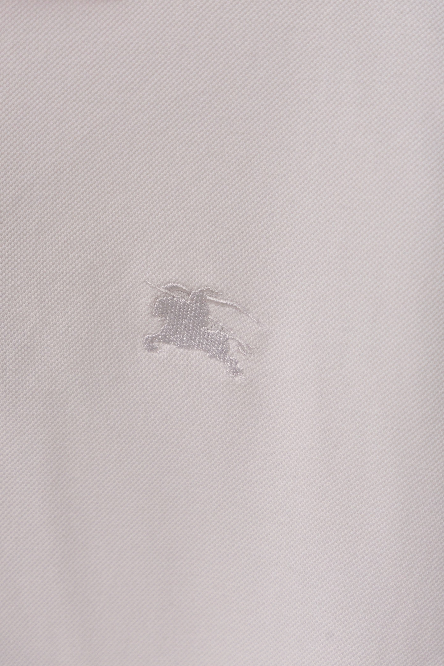 Burberry polo shirt fabric close-up with small embossed horse logo