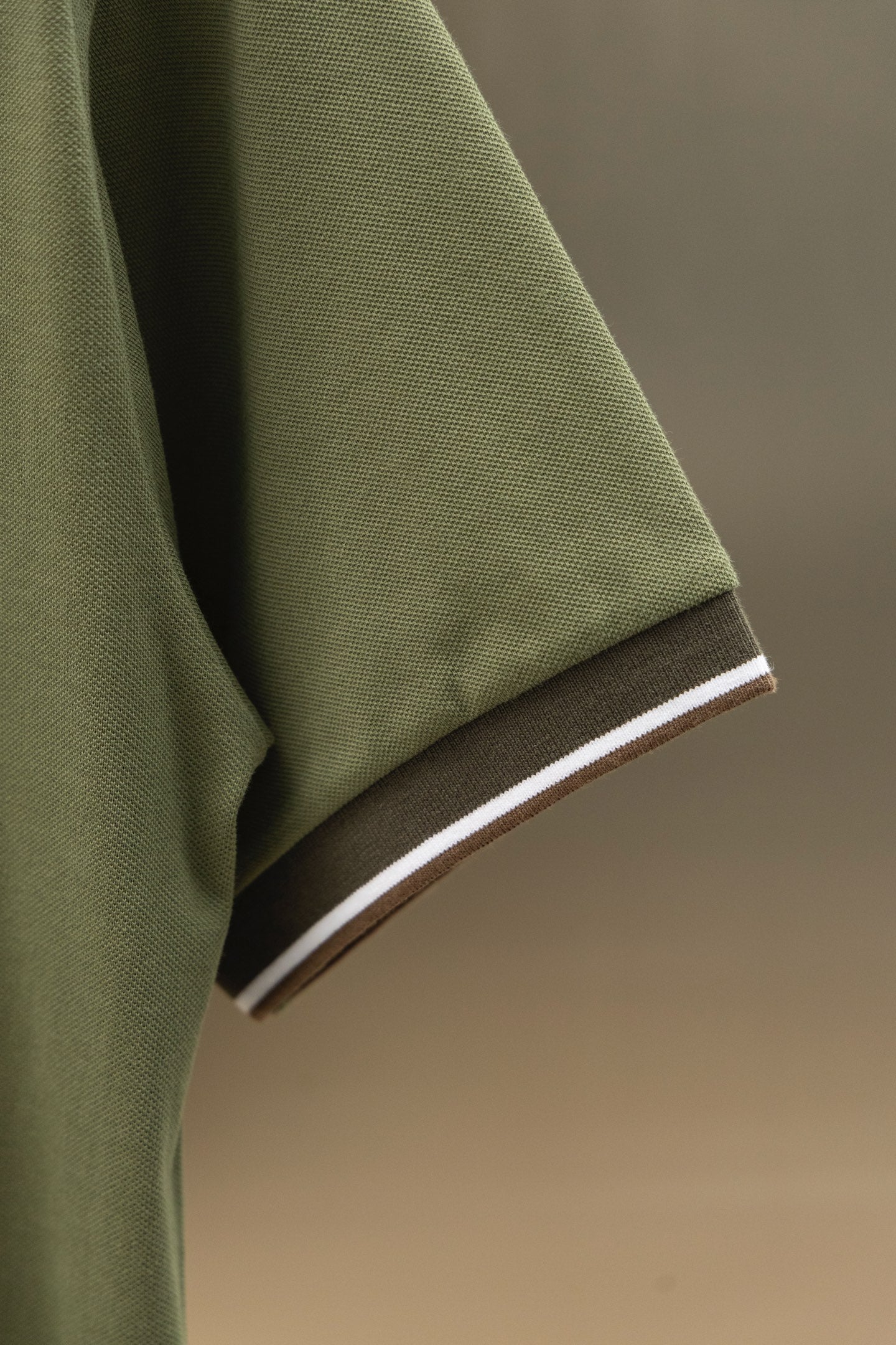 Burberry polo shirt sleeve cuff with striped trim on olive green fabric